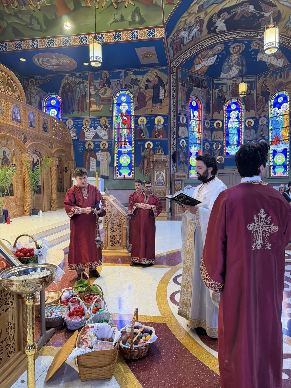 Fr. Dragan Vuković blessing the Paschal baskets with altar servers before the iconostasis